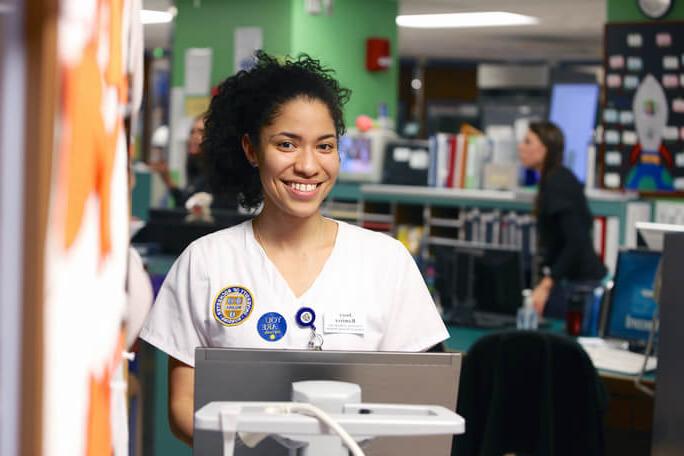 Employee at laptop smiling at University of Rochester Medical Center